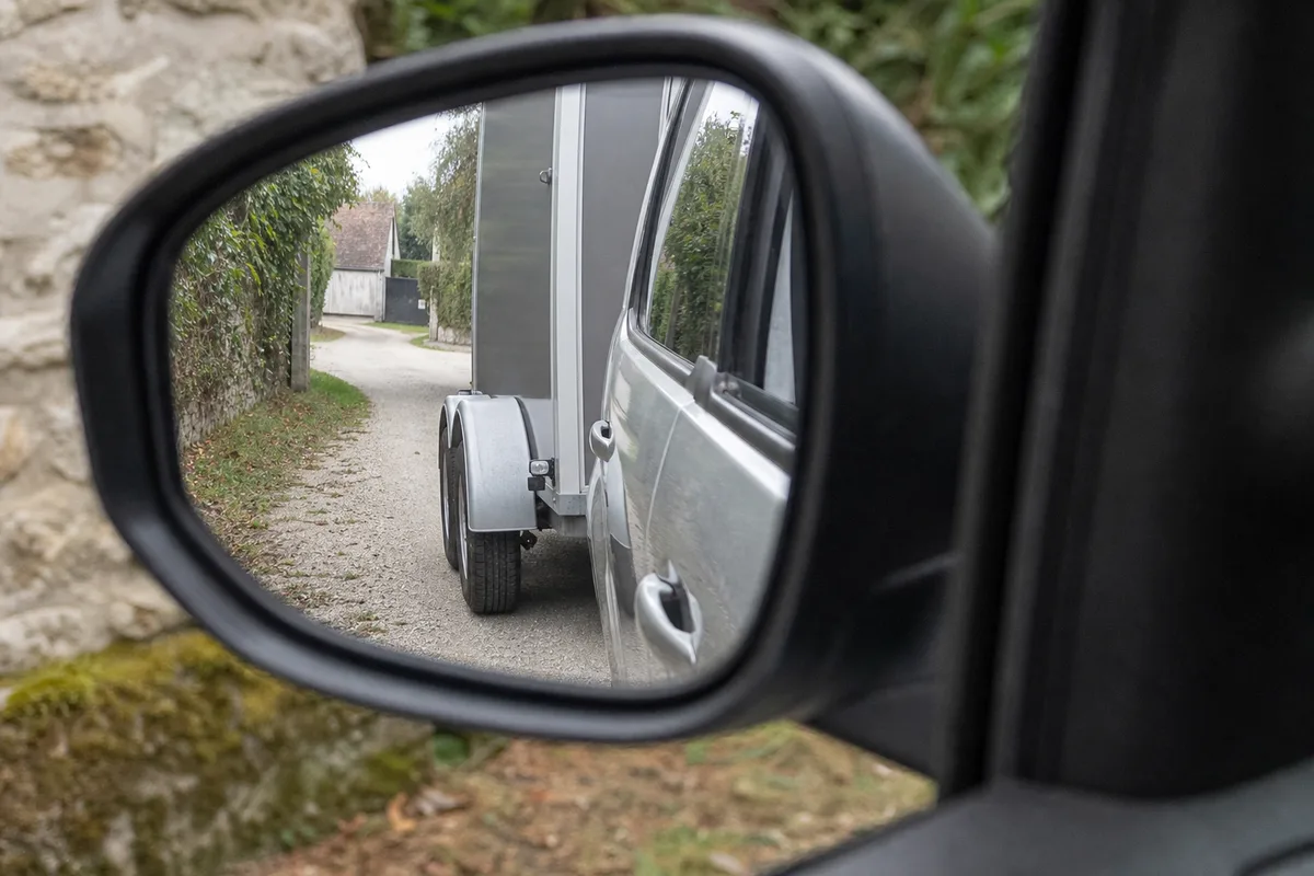 Rétroviseur extérieur de voiture reflétant le flanc et la roue d&rsquo;une remorque lors d&rsquo;une manœuvre de recul